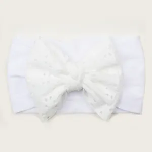 Détail du bandeau bébé blanc en nylon avec broderie anglaise et un grand nœud souple