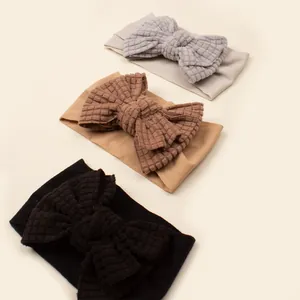 Close-up of three waffle knit bow headbands in grey, tan, and black for infants