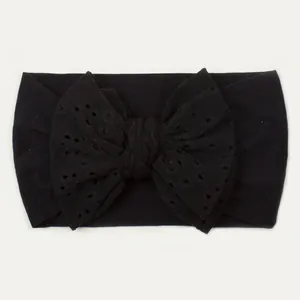 Détail du bandeau bébé noir en nylon avec motif ajouré sur un grand nœud papillon