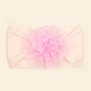 Macro-opname van roze baby nylon hoofdband met grote gelaagde kanten bloem decoratie
