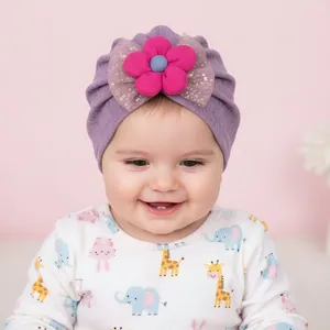 Detail of baby turban hat with golden glitter mesh bow and large pink floral decoration