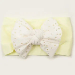 Détail du bandeau bébé en nylon souple avec noeud brodé ajouré de couleur crème douce