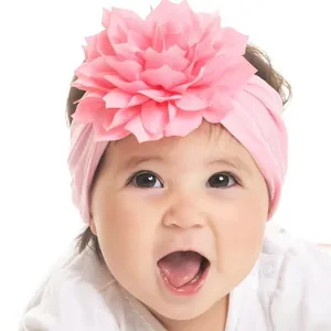 Close-up of a soft pink baby headband with a large fabric flower on an infant model