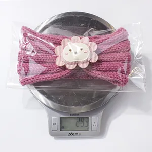 Close-up of pink knitted baby headband with a cute lion ornament on a digital scale