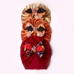 Detailed view of three velvet baby beanies with bat wings and Halloween bows