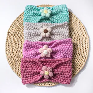 Dettaglio di quattro fasce per neonati in maglia con fiori all'uncinetto su tappeto