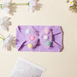 Detail eines Baby Stirnbands mit lila Netzschleife und bunten Makronen Pompons