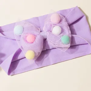 Lila Baby-Stirnband mit großer Netzschleife gefüllt mit bunten Macaron-Pompons