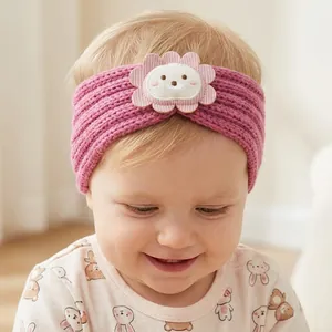 Close-up of pink knit baby headband with cartoon patch and soft scalloped edges