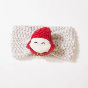 Detail eines gestrickten Baby-Stirnbands in Creme mit einer weichen Weihnachtsmann-Figur