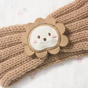 Close-up of baby knit headband with cute brown lion embroidery on soft ribbed wool