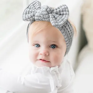 Detail view of baby headband with large waffle knit bow in soft grey fabric