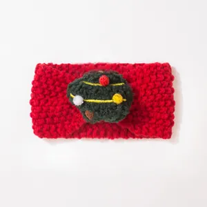 Detailaufnahme eines roten Strick-Baby-Stirnbands mit festlichem grünen Bommel-Weihnachtsbaum