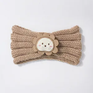 Detail of baby knitted headband featuring a cute cartoon lion patch on khaki wool fabric