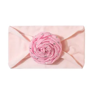 Detailed view of a soft pink baby headband featuring a fabric rose with silver stars