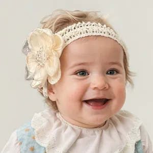 Close-up van een baby met een ivoren kanten hoofdband en een champagnekleurige parelbloem