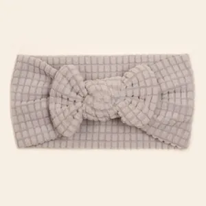 Detail of grey waffle knit baby headband featuring a soft large bow ornament