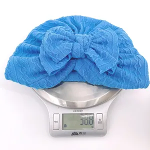 Vue détaillée du bonnet turban bleu léger pour bébé en maille gaufre avec grand nœud