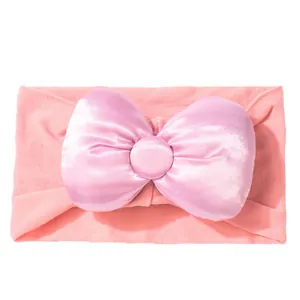 Detail van zachte roze elastische baby hoofdband met grote paarse satijnen strik