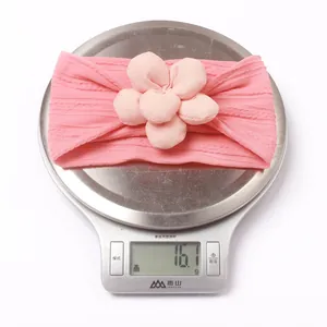 Détail montrant le poids de 16,1g du bandeau rose pour bébé sur une balance