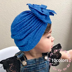 Bonnet turban bébé bleu roi en maille gaufrée avec grand nœud porté par un enfant