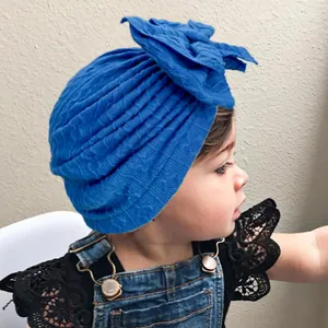 Gros plan d'un bonnet turban bleu roi pour bébé avec un grand nœud en tissu tricoté