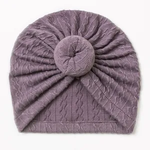 Close-up of deep purple knit baby donut turban hat with intricate cable stitch texture