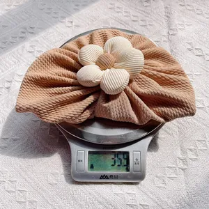 Détail du bonnet turban bébé avec tissu plissé doux et grande fleur en velours côtelé
