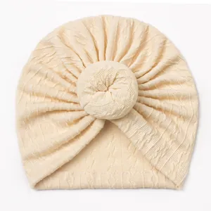 Cream knit baby turban hat featuring jacquard weave and a cute donut twist knot design