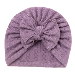Détail du bonnet tricoté pour bébé violet avec grand nœud et motif de torsades