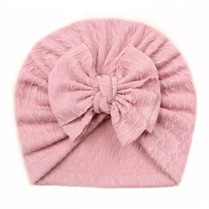 Détail du bonnet turban rose pour bébé en tricot côtelé doux avec un grand nœud décoratif
