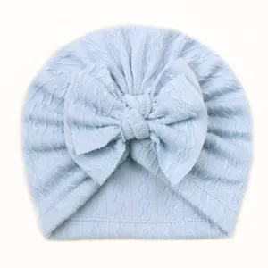 Gros plan du bonnet turban bleu clair pour bébé avec maille torsadée et grand nœud