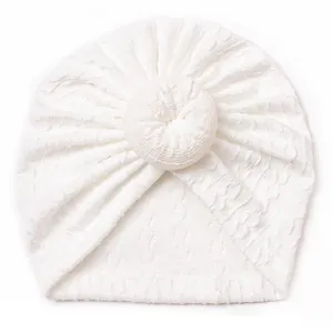 Detail of soft white baby donut hat showing textured knit fabric and decorative knot