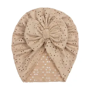 Ademende beige baby tulband muts met een grote strik en decoratieve oogjesgaatjes