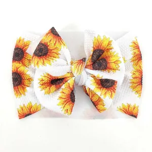 Detalle de la diadema para bebé con estampado de girasoles y lazo grande de punto