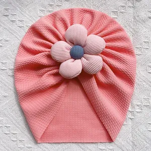 Turban rose en maille gaufrée pour bébé avec grande fleur 3D sur fond blanc