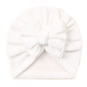 Détail d'un bonnet turban blanc pour bébé avec un grand nœud décoratif élégant
