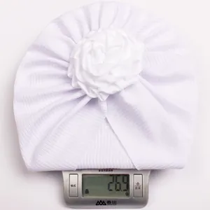 Detailed view of lightweight white floral infant turban weighing only 26.9 grams on scale