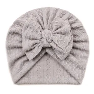 Bonnet turban en tricot gris clair pour bébé avec grand nœud sur fond blanc uni