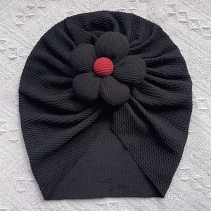 Détail du turban pour bébé en maille gaufrée noire avec centre de fleur rouge