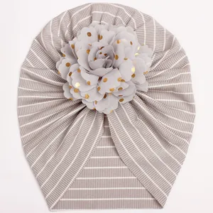 Striped baby turban hat with oversized gold polka dot flower decoration in taupe color