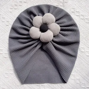 Détail du bonnet turban bébé gris foncé avec fleur beige et texture à bulles douces