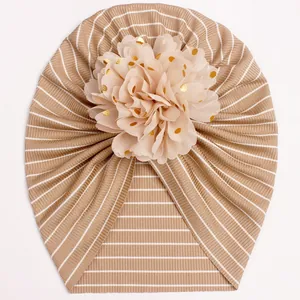 Detailed view of striped baby turban hat featuring a champagne gold sequin chiffon flower