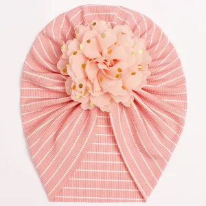 Detail of baby turban hat with pink stripes and large floral ornament with gold dots