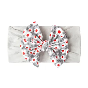 Détail d'un bandeau bébé souple avec grand nœud floral et tissu gris respirant et doux