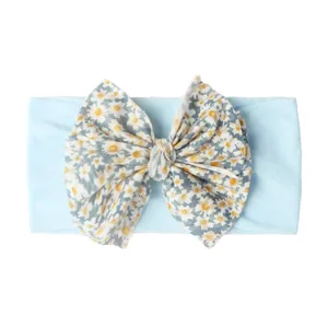 Détail d'un bandeau doux pour bébé avec un ruban bleu clair et un grand nœud marguerite