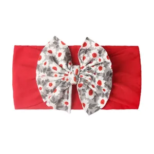 Gros plan sur le bandeau bébé rouge avec nœud floral en tricot doux et détails de couture