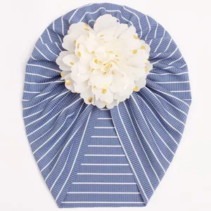 Close-up of baby striped turban hat featuring a large gold foil polka dot floral detail