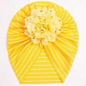 Detailed close-up of ribbed yellow baby turban hat with golden polka dot mesh flower