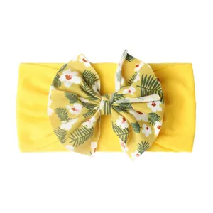 Détail du bandeau bébé en maille jaune avec motif floral tropical sur le nœud